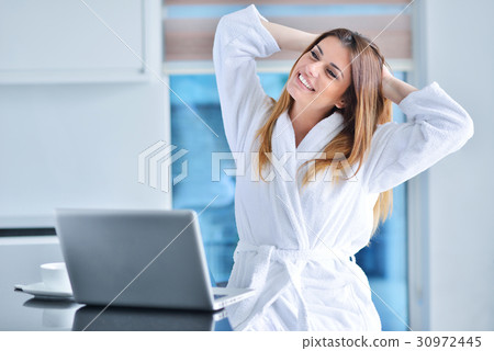 woman wearing a white bathrobe with laptop woman wearing a white bathrobe with laptop 30972445