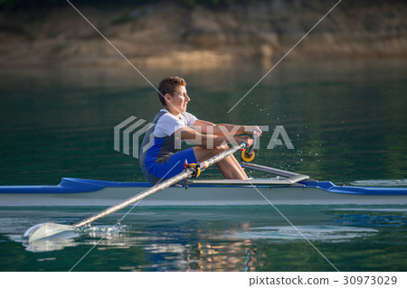 A Young single scull rowing competitor paddles on 30973029