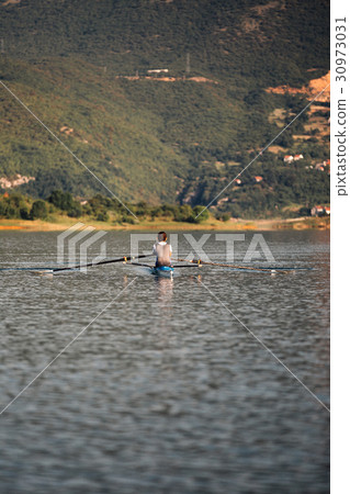 A Young single scull rowing competitor paddles on 30973031
