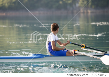 A Young single scull rowing competitor paddles on A Young single scull rowing competitor paddles on 30973057