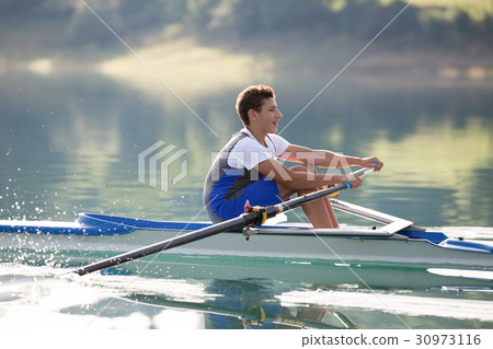 A Young single scull rowing competitor paddles on 30973116