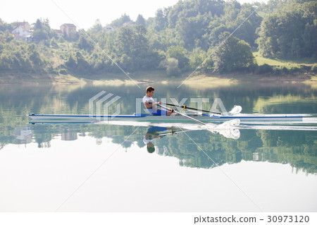 A Young single scull rowing competitor paddles on A Young single scull rowing competitor paddles on 30973120
