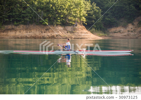 A Young single scull rowing competitor paddles on A Young single scull rowing competitor paddles on 30973125