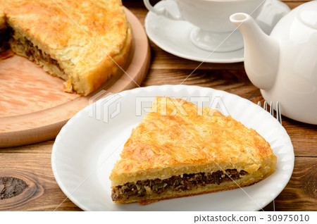 Piece of pie with minced meat on wooden table. 30975010