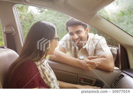 Man leaning on car window talking to woman 30977054