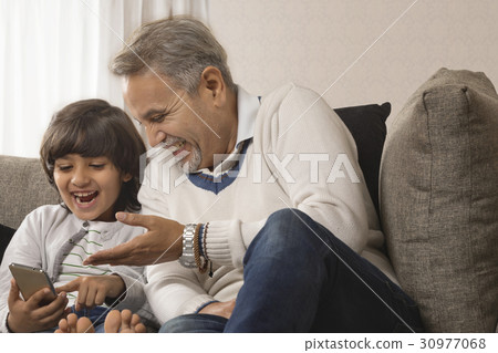 Smiling grandfather and grandson using mobile phone Smiling grandfather and grandson using mobile phone 30977068