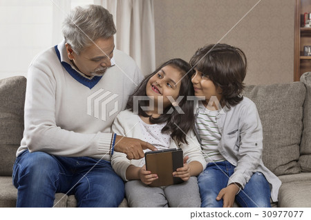 Happy grandfather and grandchildren using digital tablet Happy grandfather and grandchildren using digital tablet 30977077