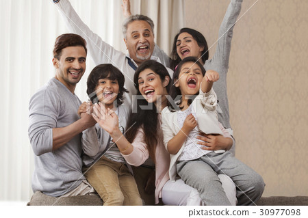 Cheerful multi-generation family sitting together Cheerful multi-generation family sitting together 30977098