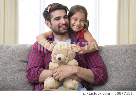 Father wearing make up posing with daughter holding teddy bear 30977191