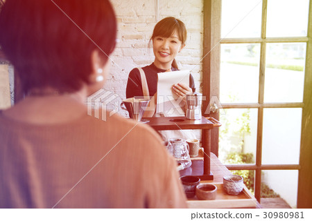 Young woman barista talking with customer 30980981