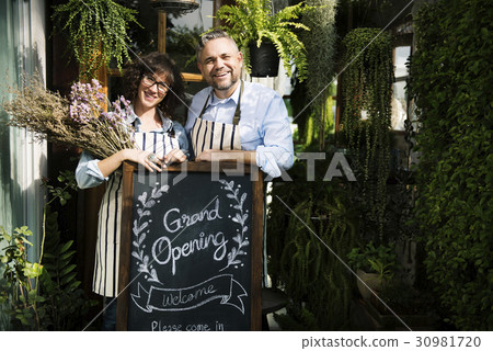 Adult Man and Woman Standing with Grand Opening Sign Adult Man and Woman Standing with Grand Opening Sign 30981720