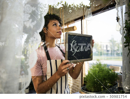 Woman Hanging Open Sign by the Glass Window 30981754