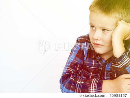 Young boy sitting and being serious Young boy sitting and being serious 30983167