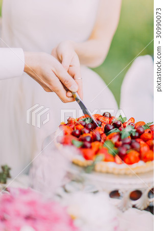 The close-up photo of newlyweds` hands holding the The close-up photo of newlyweds` hands holding the 30990073