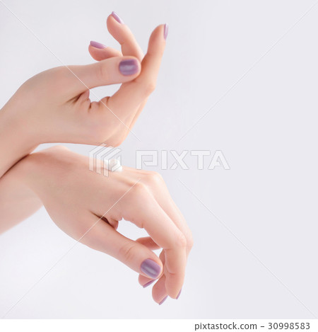 Women's hands with pink manicure applying cream. Women's hands with pink manicure applying cream. 30998583