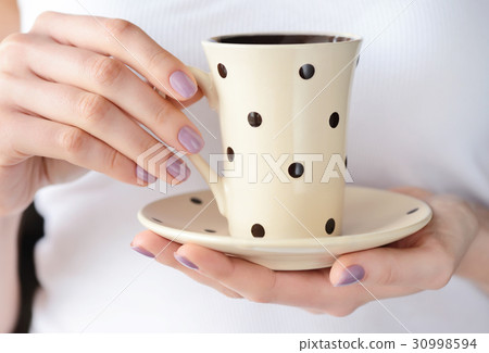 Hands of a young woman holding a cup Hands of a young woman holding a cup 30998594