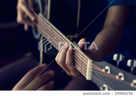 Female hands learning to play on acoustic guitar 30999256
