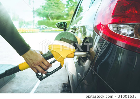 Man's hand pumping gasoline fuel in car. 31001635