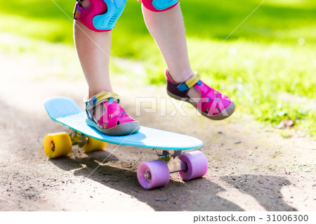 Child riding skateboard in summer park 31006300
