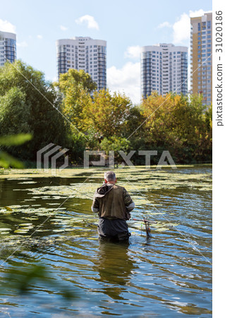 Old fisherman fishing in a lake or river with a Old fisherman fishing in a lake or river with a 31020186
