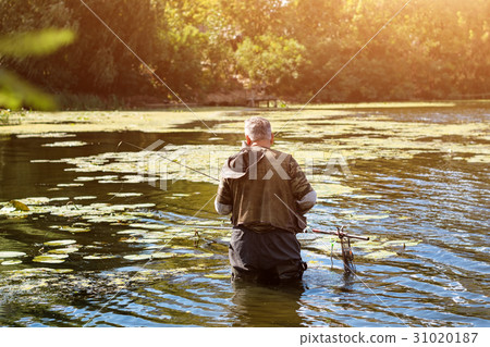 Old fisherman fishing in a lake or river with a Old fisherman fishing in a lake or river with a 31020187