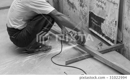 WORKER CUTTING STEEL WITH ELECTRIC WHEEL GRINDER 31022994