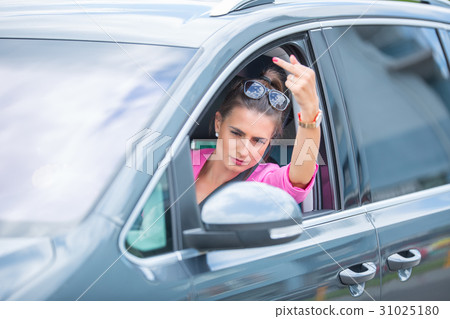 Attractive woman shows obscene gesture from a car Attractive woman shows obscene gesture from a car 31025180