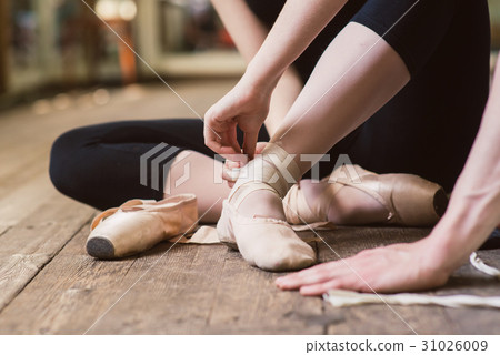 Ballerina putting on her ballet shoes 31026009