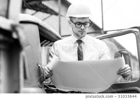 Engineer builder in a helmet holds drawings at Engineer builder in a helmet holds drawings at 31033644