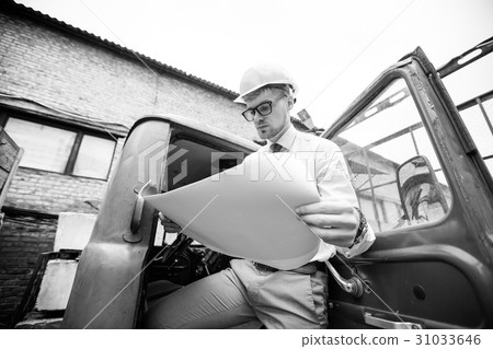 Engineer builder in a helmet holds drawings at Engineer builder in a helmet holds drawings at 31033646