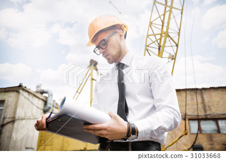 Engineer builder in a helmet holds drawings at 31033668