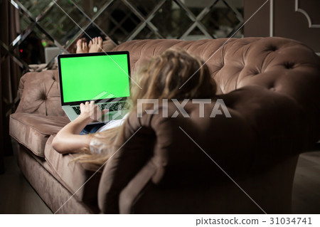 Blonde lying on the sofa with the laptop. Green Blonde lying on the sofa with the laptop. Green 31034741