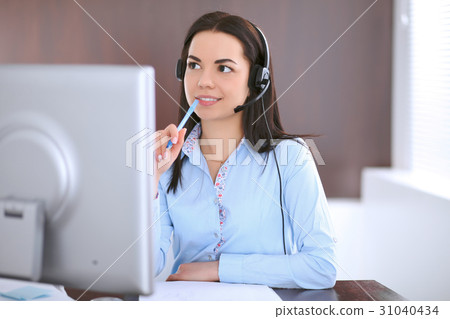 Young business woman in a headset, sitting at the Young business woman in a headset, sitting at the 31040434