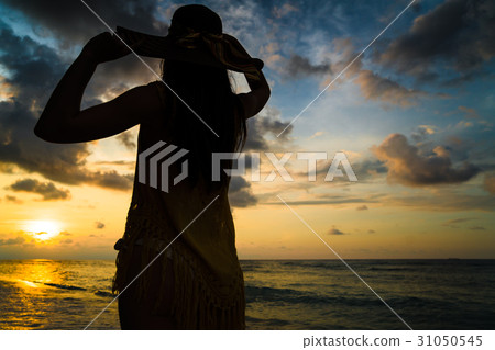 Tourist woman watching sunset at ocean beach Tourist woman watching sunset at ocean beach 31050545