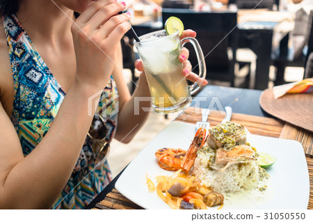 Woman patron eating seafood and drinking cocktail 31050550