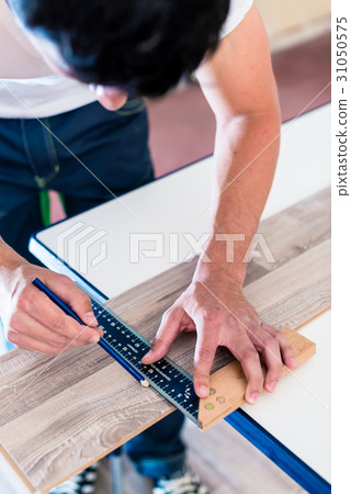 Carpenter marking cut on parquet piece Carpenter marking cut on parquet piece 31050575