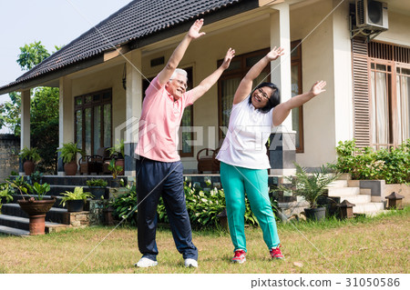 Active senior couple exercising with raised arms Active senior couple exercising with raised arms 31050586