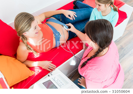 Young girl watching midwife attaching CTG to Young girl watching midwife attaching CTG to 31050604