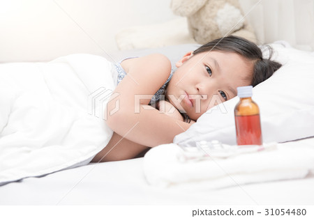 sick girl lying in bed and medicine syrup 31054480