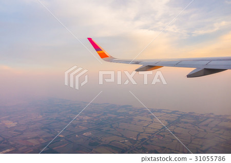 Wing of an airplane flying above the clouds at sunset . Wing of an airplane flying above the clouds at sunset . 31055786