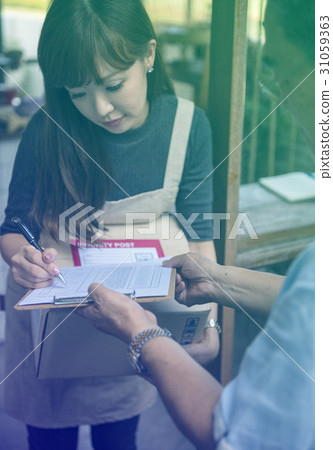 Young woman receive a parcel and sign the document Young woman receive a parcel and sign the document 31059363