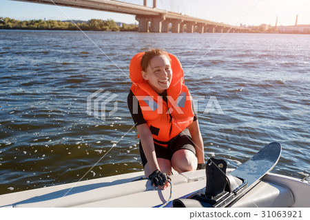 Young fit woman ready to ride water skis siting on 31063921
