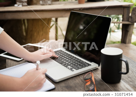 Girl hands. Laptop and cup of tea on wooden table 31071454