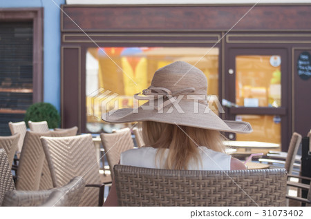 woman with hat sitting on restaurant terrace woman with hat sitting on restaurant terrace 31073402
