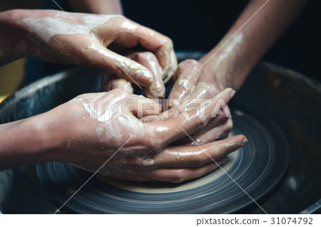 Two people mold a clay pot from white clay. Two people mold a clay pot from white clay. 31074792
