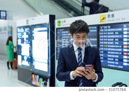 A businessman looking at a smartphone in the arrival lobby in the airport 31075768