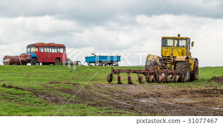 The tractor plows the land in the fields in the The tractor plows the land in the fields in the 31077467