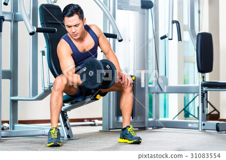 Asian man lifting hand weight at gym Asian man lifting hand weight at gym 31083554