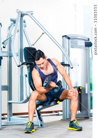 Asian man lifting hand weight at gym 31083555
