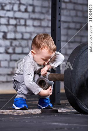 Little sporty child with barbbell against brick 31084496